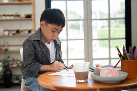 Creative Moments and Learning. A young boy focused on drawing at the table. photo