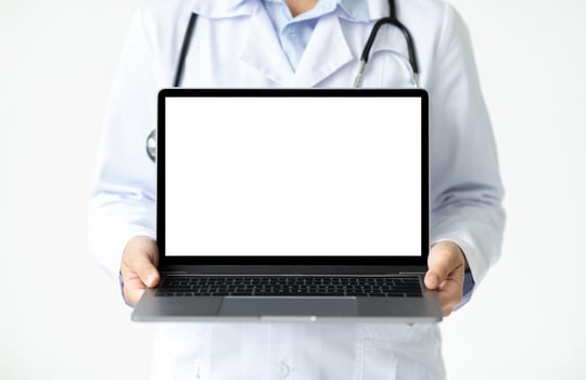 Online appointment with doc, telehealth, remote medicine concept. Laptop computer with white blank screen mockup copy space in woman doctor hands, white background photo