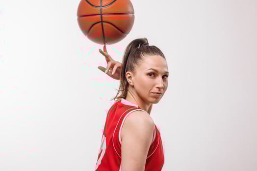 Confident female basketball player spinning ball on finger, sporty studio portrait for competition concept photo