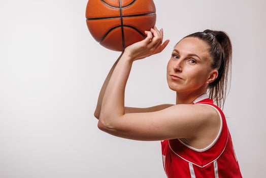 Confident female basketball player in red uniform preparing to shoot, studio sports portrait photo