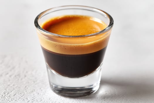 Shot Glass of Espresso with Thick Crema on White Background photo