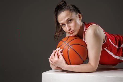 Portrait of confident female basketball player in red uniform with ball in studio, womens sports photo
