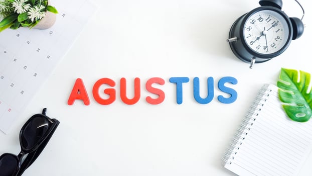 Flat lay composition with blue and red color foam letters spelling word AUGUST isolated on white background photo