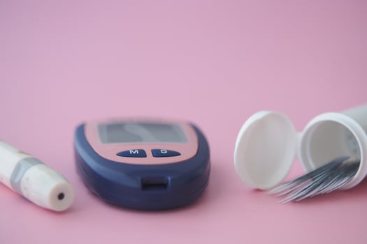 Diabetes monitoring tools on pink background photo