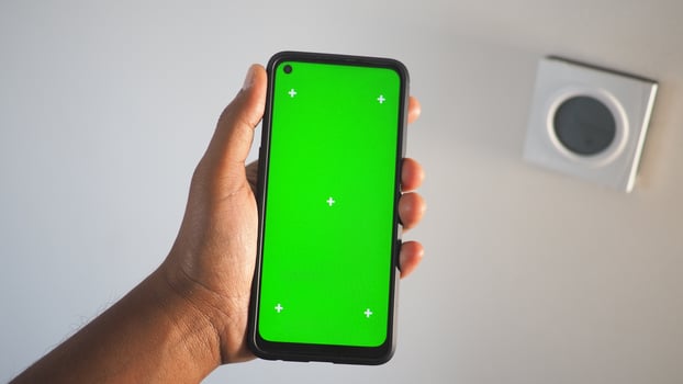 Hand holding smartphone with green screen and wall elements photo