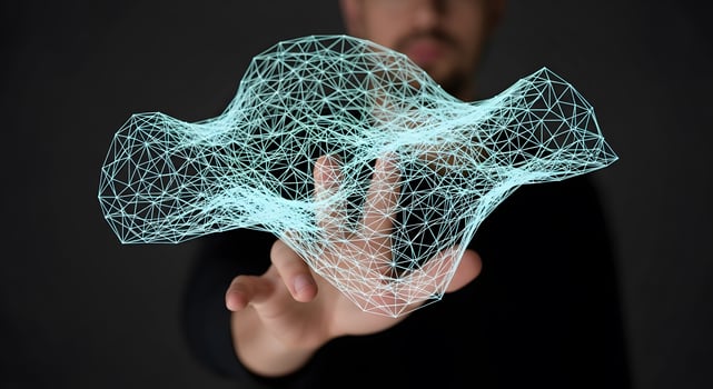 A man is holding a wireframe object photo
