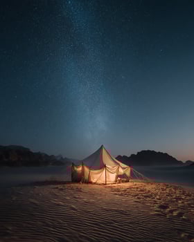 Panoramic Desert View with a Tiny Tent Glowing Under Massive Night Sky photo