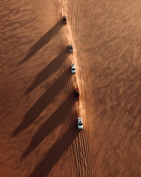 Top Down Shot of Four by Four Convoy Moving Through Curved Desert Landscape photo