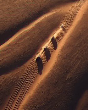 Drone Image of 4x4 Vehicles Making Tracks Over Wavy Sand Dunes in Desert photo