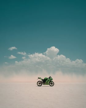 Dynamic Image of Green Motorcycle Speeding Through Salt Flat With Dust Clouds, High Contrast Colors, and Clean Sky for Automotive Stock Usage photo