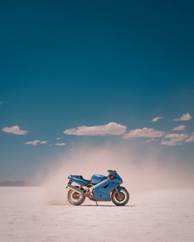 Modern Tosca Sports Bike Rushing Through Salt Desert Under Wide Sky With Dust and Empty Background in Simple and Isolated Layout photo