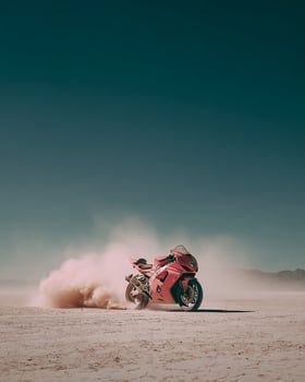 Isolated Pink Motorcycle Racing Over Salt Flat Desert With Dust Clouds Under Clear Blue Sky in a Minimal Scene of Speed and Motion photo