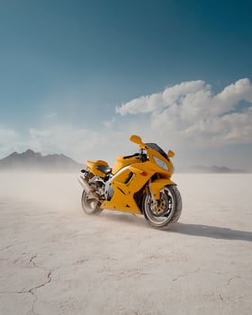 Yellow Sports Motorcycle Accelerating Over Salt Desert With Dust Blowing and Blue Sky in Minimal and High Contrast Landscape photo