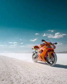 Sleek Orange Sports Bike Speeding on White Salt Desert Under Bright Blue Sky With Dust Clouds and Minimalist Visual Setting in Side View photo