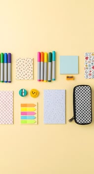 A variety of stationery items laid out on a yellow background photo