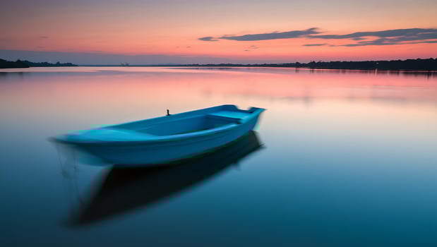 Blue boat on calm water at sunset photo