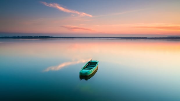 Tranquil Dawn Over Calm Lake with Solitary Green Rowboat Reflecting Pastel Sky photo