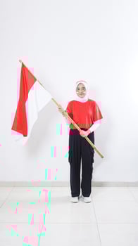 Beautiful muslim Asian girl celebrate Indonesia independence day in red and white outfit by holding Indonesian flag isolated on white background photo