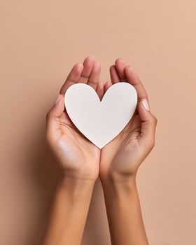 Hands Holding White Heart Shape Card on Beige Background photo