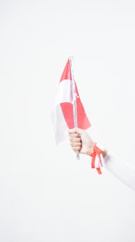 A woman hand with red and white Indonesia flag color attribute holding mini Indonesia flag decoration to celebrate Indonesia independence day celebration isolated on white background photo