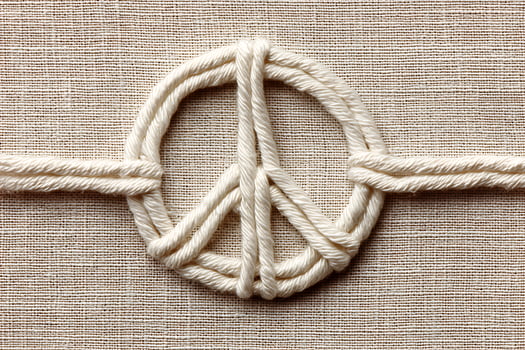 White Rope Peace Sign on Beige Fabric Background photo
