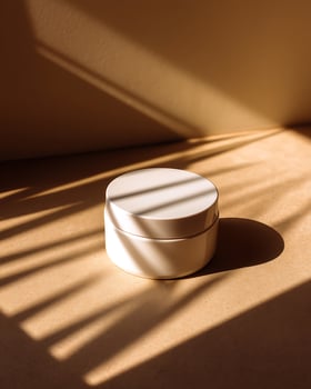 Minimalist White Cosmetic Jar with Shadows on Beige Surface in Warm Natural Light photo