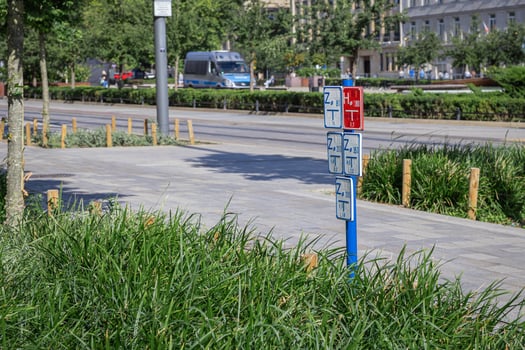 Multiple white and red utility signs displaying technical codes and measurements on a blue pole, crucial for urban infrastructure planning and public service management in a city photo