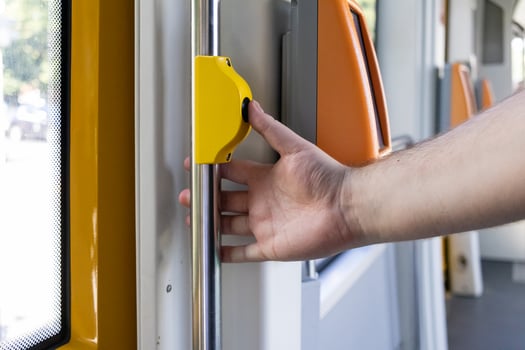 Hand pressing an essential yellow stop request button inside a modern public transport vehicle, indicating passenger's desire to exit at the next station photo