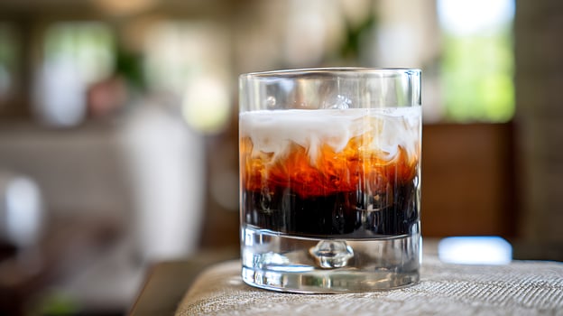 Creamy Coffee Drink Swirls Inside a Glass on a Textured Surface. photo
