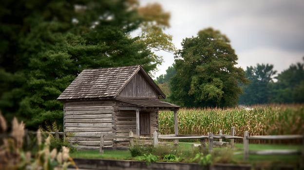 Rustic wooden cabin beside a lush cornfield in the countryside. photo