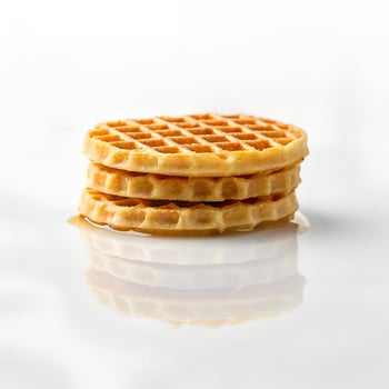Minimalist style photo of single waffles with reflection on glossy white surface, soft shadows