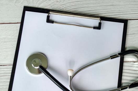Top view of medical form on clipboard with pen and stethoscope with customizable space for text or message photo