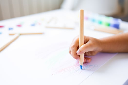 Young child drawing with colored pencils on white paper photo