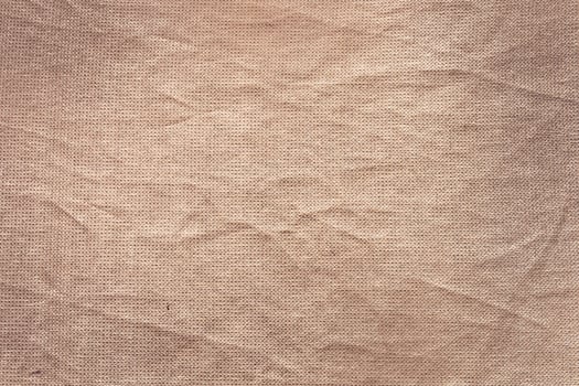A close-up view of textured fabric with a soft, beige color. The surface shows subtle wrinkles and a natural, organic appearance. photo
