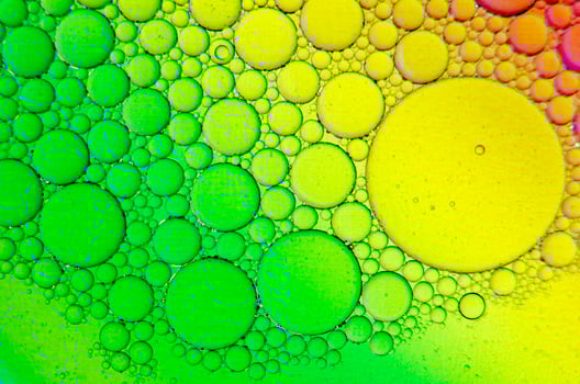 Close up of oil on water, reflecting a subtle green and yellow gradient background photo
