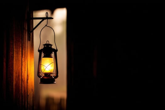 Soft glow of a lantern illuminating a rustic wooden wall during twilight hours in an outdoor setting photo