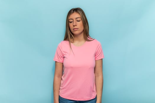 Sad woman wearing pink t-shirt for World Breast Cancer Day looking down photo