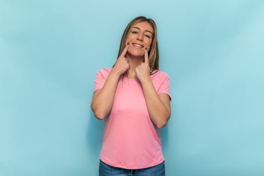 Woman wearing pink t-shirt for World Breast Cancer Day is smiling and pointing her cheeks photo