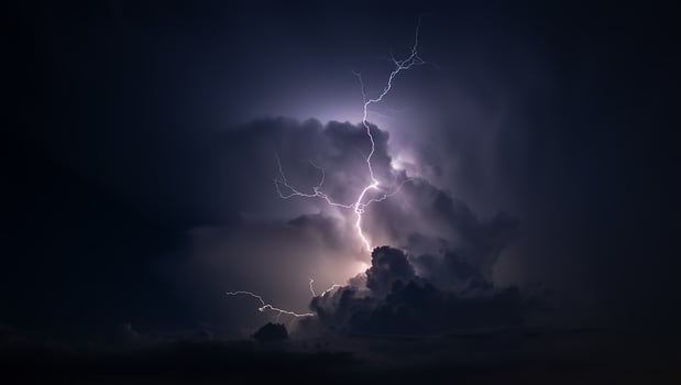 Lightning strikes through the clouds at night photo