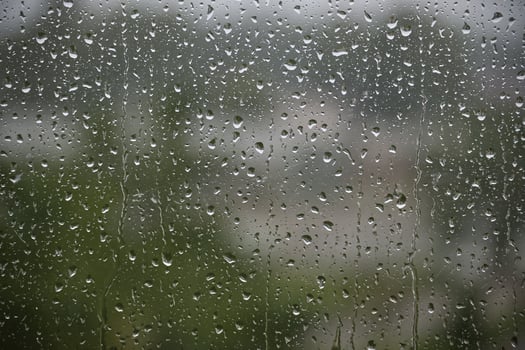 Rain Drops on Glass Window With Blurry Outdoor Background in Focus photo