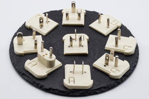 A collection of diverse international electrical travel adapters arranged on a dark slate surface, essential for global power connectivity. photo