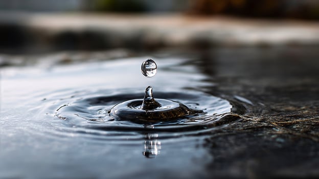 Droplet of water hitting a dark, shiny reflective surface photo