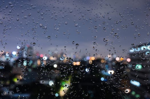 Rain drops on glass window in monsoon season with bokeh of city lights background. photo