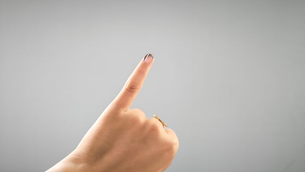 Woman's Hand with Inked Finger Pointing Up After Voting in Election photo