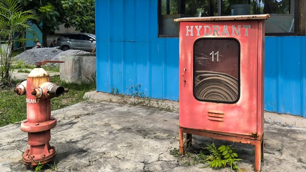 Vintage fire protection equipment including a hydrant and hose cabinet number 11 on a cracked concrete base. photo