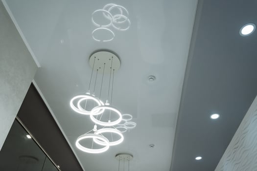 A modern chandelier featuring a unique ring design that elegantly casts beautiful light reflections across the ceiling, enhancing the ambiance of the entire room with its stunning visual effect photo