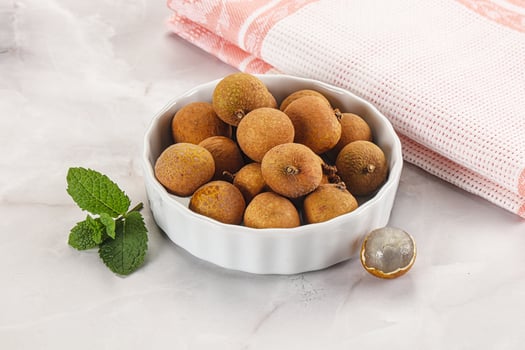 A bowl of fruit and a spoon with a nut in it photo