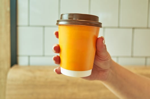 Person is holding a cup with a brown lid photo