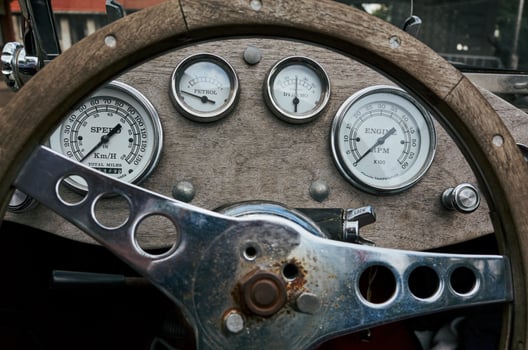 The steering wheel of a vintage car has a few gauges on it photo