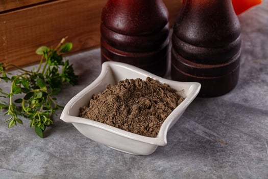 A bowl of brown powder next to two bottles of ketchup photo